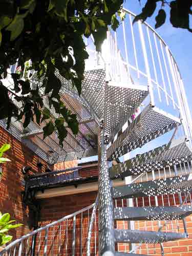 looking up the underside of perforated steps on a outdoor spiral staircase