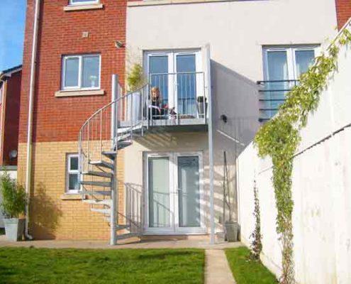 lady on top of an outdoor balcony to back of house with spiral staircase