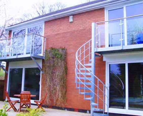 back of house with two balconies , one with a spiral staircase