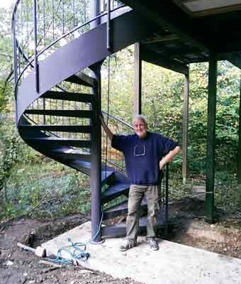 man standing next to an outdoor spiral stair
