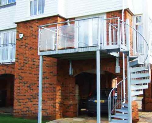 balcony outside with glass balustrade and a spiral staircase in steel