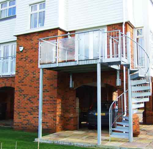 balcony outside with glass balustrade and a spiral staircase in steel