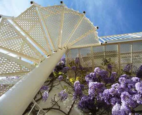 looking up at a white outdoor spiral stair with blue sky beyond