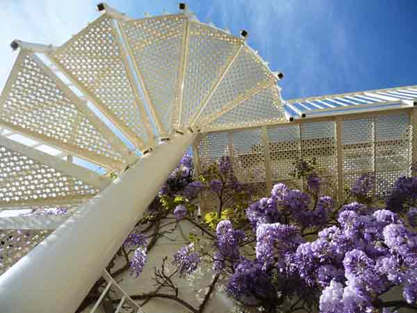 looking up at a white outdoor spiral stair with blue sky beyond