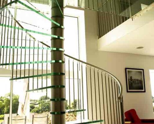 stainless steel handrail and spindles on a glass spiral stair in front of a window
