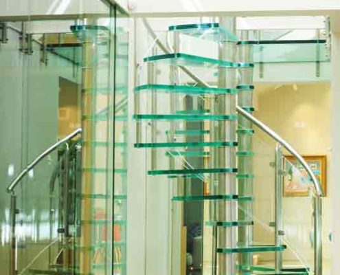 glass spiral staircase on tiled floor alongside a mirror