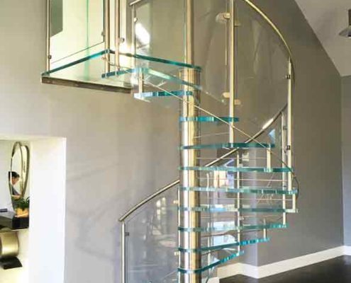 dark timber floor with a spiral stair with glass steps and curved glass panels