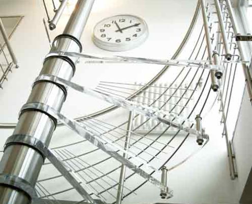 top transparent platform of a spiral stair with clock on wall