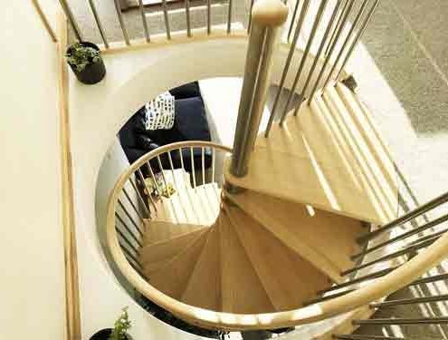 looking down on the circular opening in the floor with a spiral stair