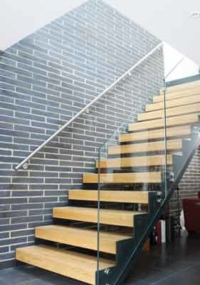 modern open riser stair in front of a brick wall