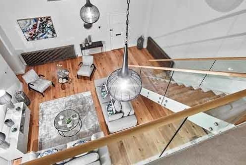 looking down on a living area with wood floor and modern staircase