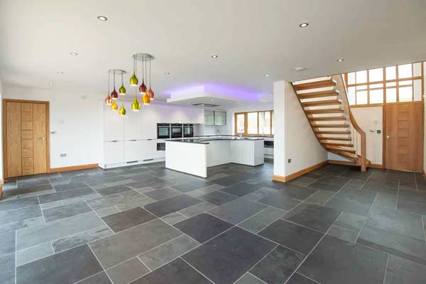 large grey tiled living area with kitchen and modern stair on show