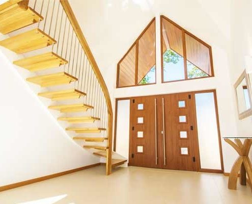 tiled floor in hallway with wooden front door and modern open staircase