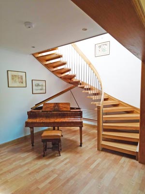 curved wooden staircase with piano