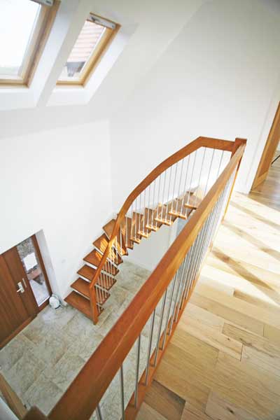 looking down on hallway with a beech floating staircase in front of a white wall