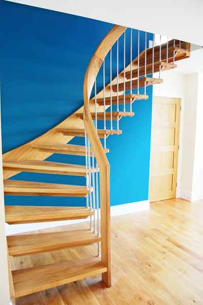 a wooden open riser staircase set Infront of a blue wall