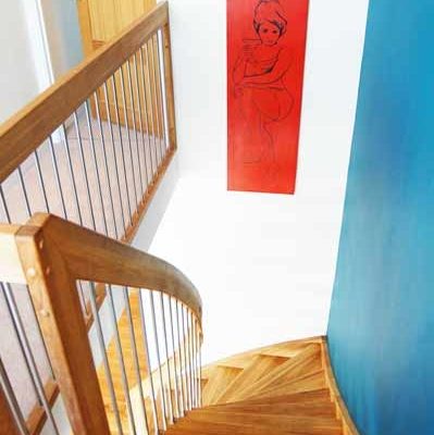 white wall with red picture and blue wall alongside an oak staircase
