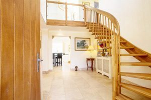 tiled floor with curving oak staircase rising