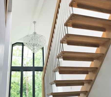huge hallway featuring a straight flight wooden staircase with large window behind