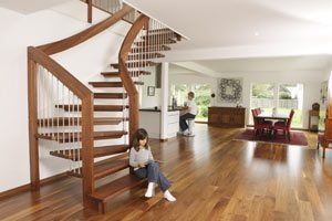 girl sitting on bottom step of floating timber staircase in large room