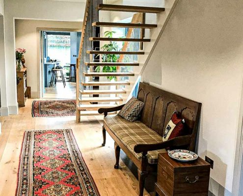 hallway with rug runner and straight flight open staircase