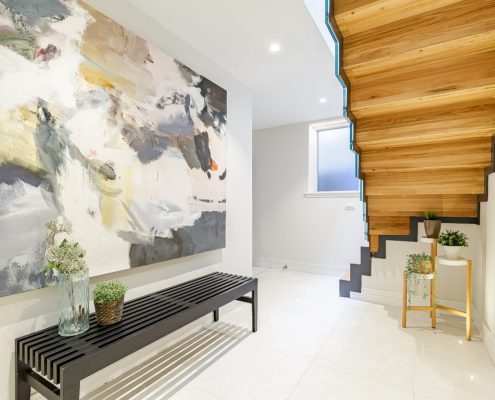 underside of oak closed riser stair with large painting on wall