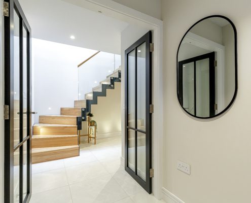 tiled floor and doorway opening into hallway with modern oak staircase