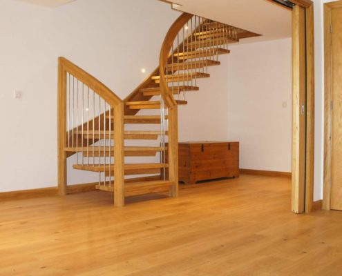 turning oak stair with open risers and a curved handrail