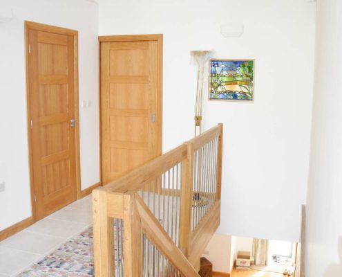 hallway looking down an oak staircase with spindles