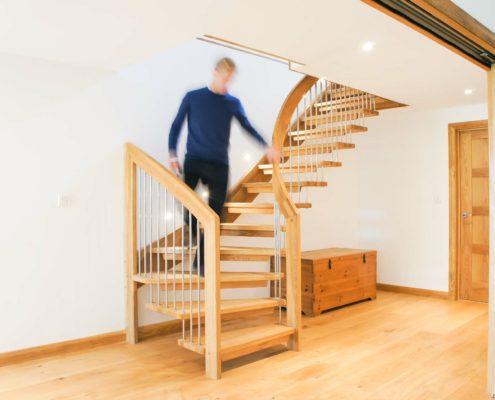 man descending a floating oak staircase with white wall and oak floor below
