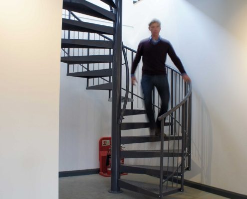 man walking down a dark grey spiral staircase