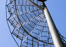underside of grated steep spiral stair with blue sky beyond