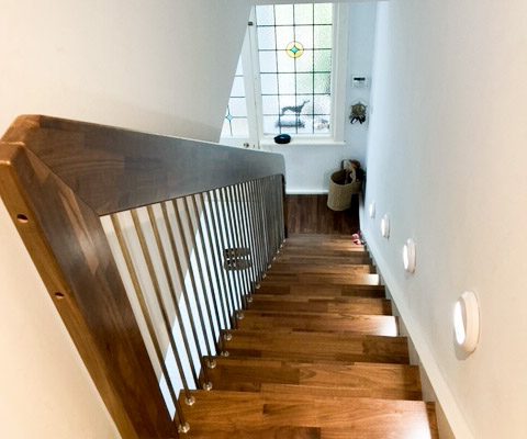 looking down a straight flight dark wood stair in a home