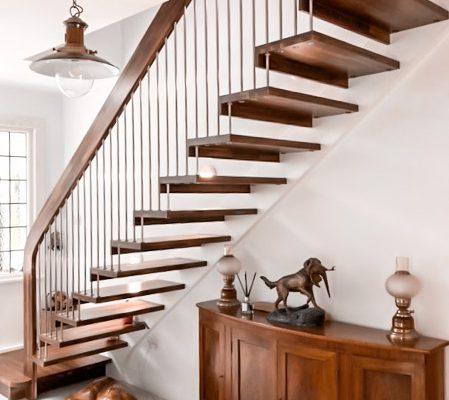 hallway with straight dark wood floating staircase with dog sitting underneath