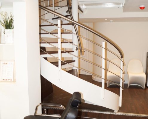 beauty salon with chair in foreground and white spiral stair to rear