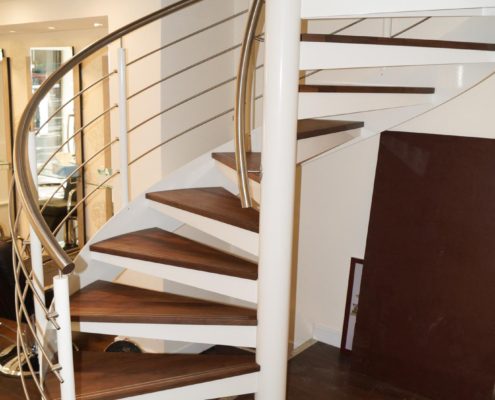 a steel spiral staircase in a shop with dark wood flooring and steps