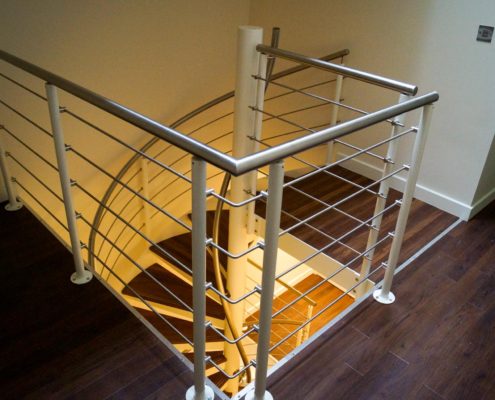 looking down a square hole with a spiral staircase with walnut steps