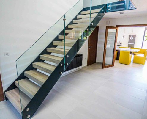 open hallway with glass and steel staircase with yellow table to rear