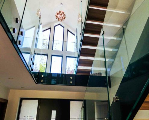 looking up at a double flight modern staircase with glass balustrade