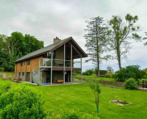 large house in garden with trees behind