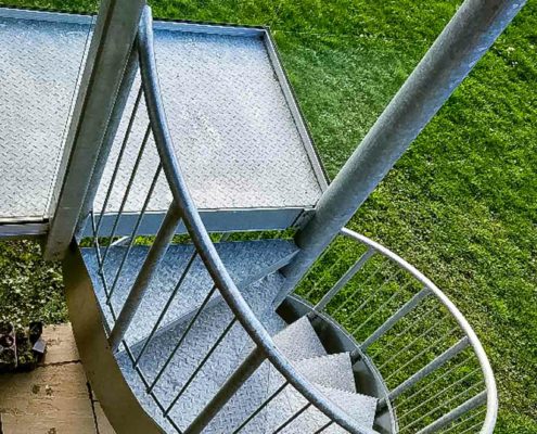 looking down on an external spiral stair with green grass behind