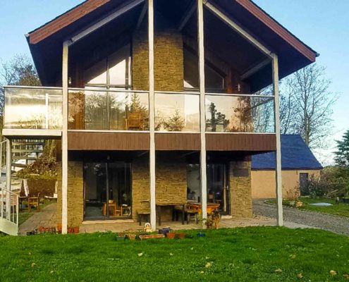 front of a home with a glass balcony and spiral staircase