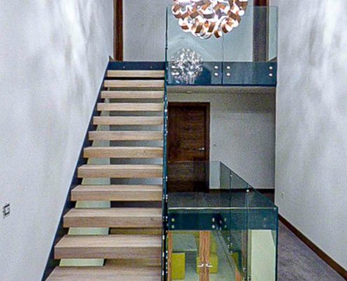 staircase with glass balustrade in landing with white walls and feature light