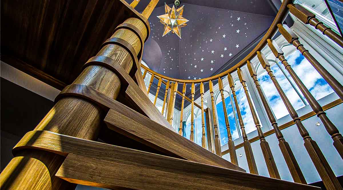 looking up at the blue painted ceiling with stars above a oak spiral staircase