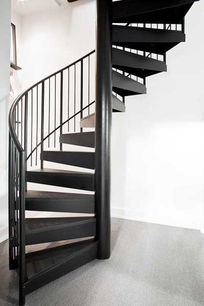 black spiral staircase with white wall behind