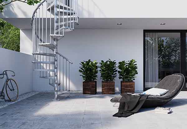 Exterior-Zink-Spiral-Staircase running up the side of a house with sun lounger on patio