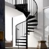 black spiral staircase in living room with rug and white wall behind