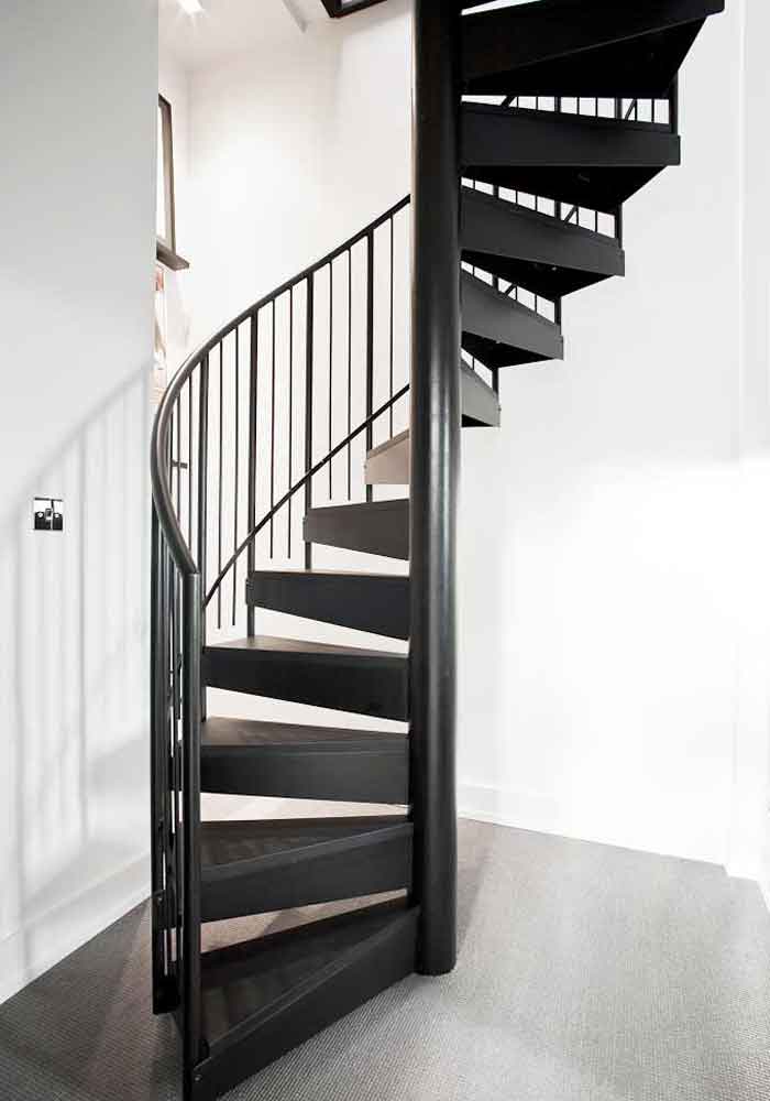 landing with black spiral stair rising up with white walls to rear