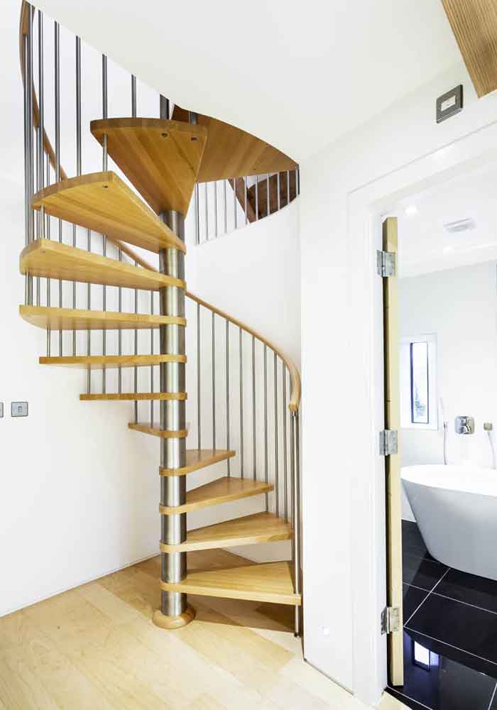 sleek oak spiral stair with stainless steel spindles in corner of white walled area