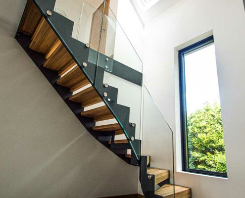 Modern stair in a hallway with window and sloping ceiling above.